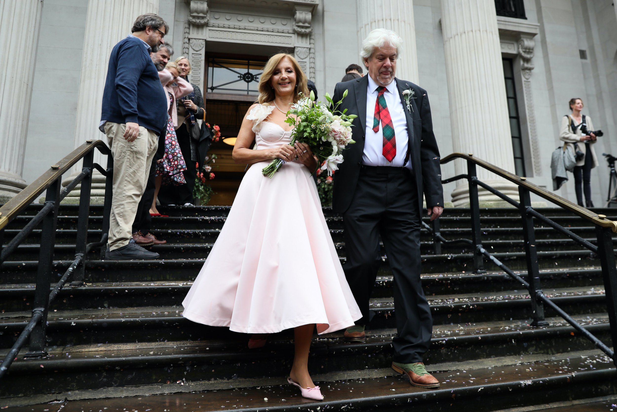 Stella and Ken hold hands while walking down the stairs after getting married in the town hall 